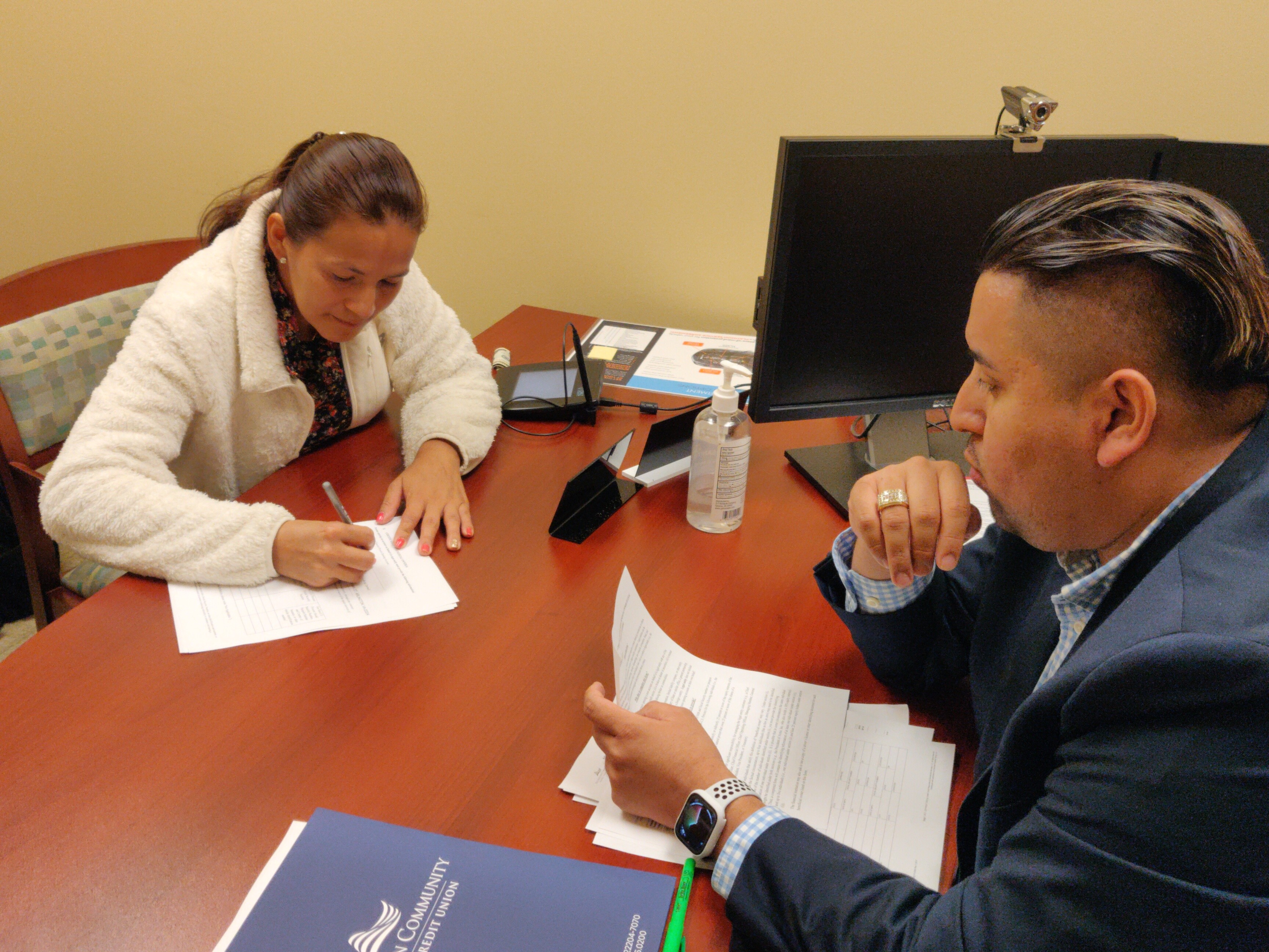 Lorena signs documents for Mujeres Manos a la Obra Bank Account at ACFCU